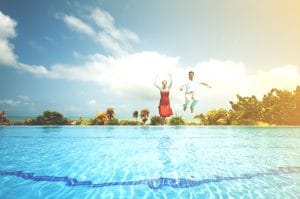 Couple jumping into clear pool