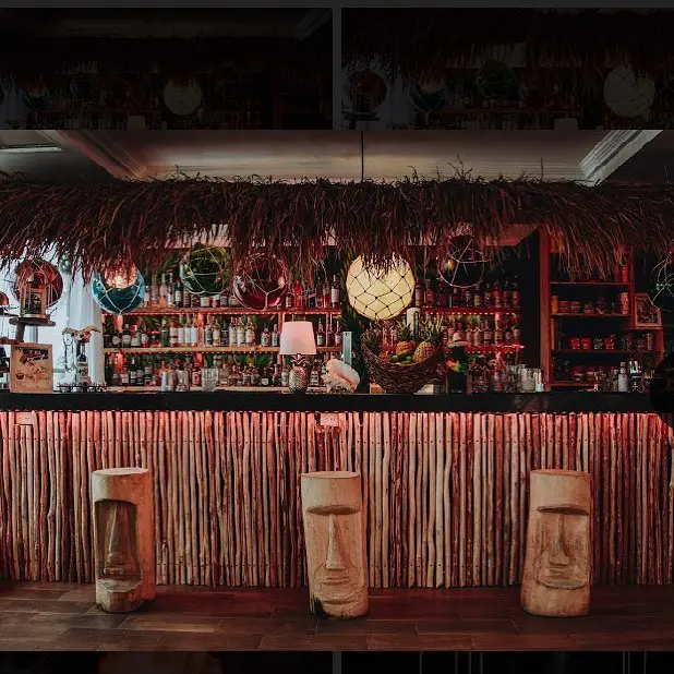 Photo courtesy of Cocomamatikiroom Bar in Cozumel, showing festive tiki-bar decor, tiki totem stools, and great lighting. 