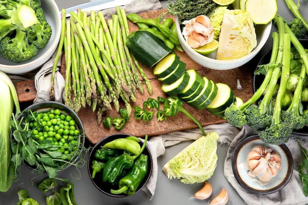 A table spread with various vegetables like asparagus, zucchini, broccoli, etc.