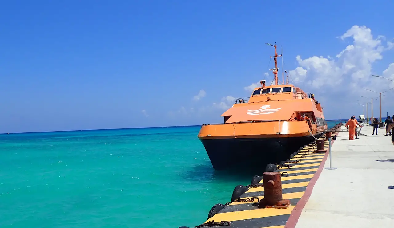 Orange Winjet passenger ferry docked a Playa del Carmen awaiting its voyage to Cozumel Island. Background of vivid turquoise water and blue sky. 