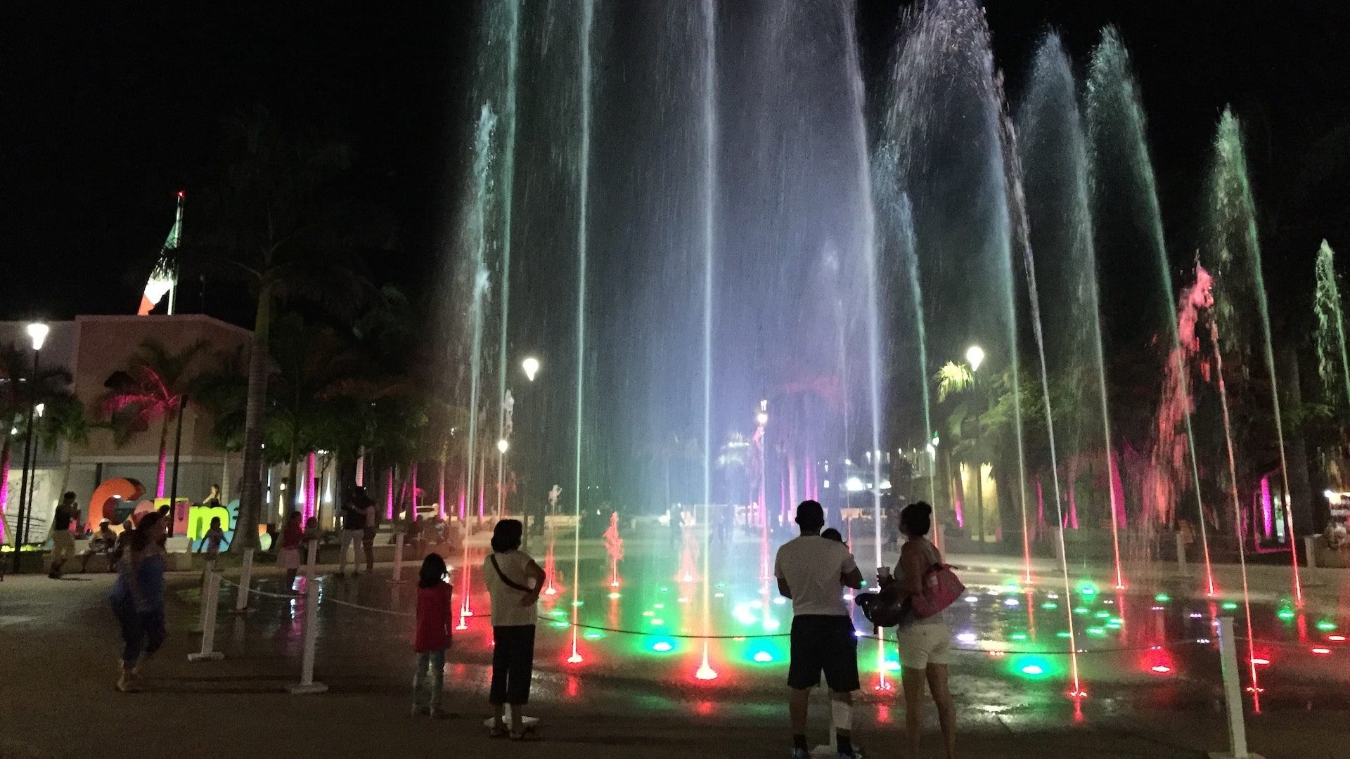 Water fountain display with colored lights in Cozumel's town square.