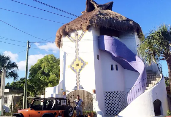 Exterior white building with purple spiral stairs and palapa.