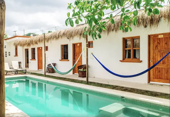 Row of hotel rooms with pool and hammocks.