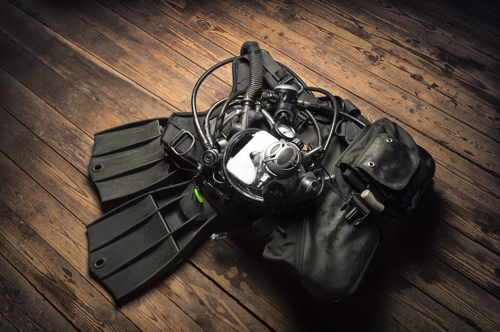 Pre-packing pile of dive gear on a wooden floor, ready to go.