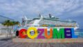 Cozumel photo op sign at the International Pier with a large cruise ship in the background.
