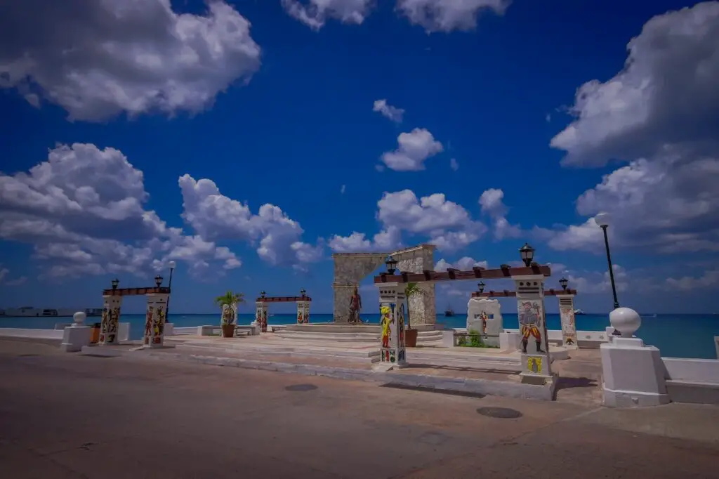 Public art installations punctuate the white malecon streets with a deep blue ocean in the background.