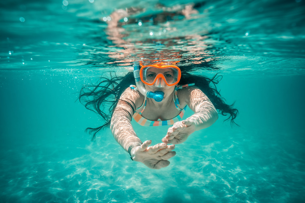 A woman snorkeling just under the surface in blue tropical ocean water.