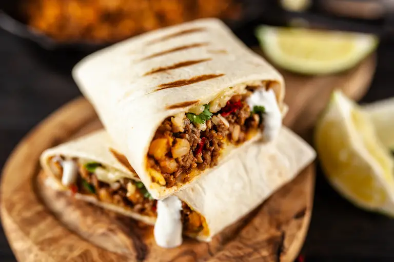 Image of burrito stuffed with Mexican ingredients, showing grill marks on the outside of the tortilla burrito.