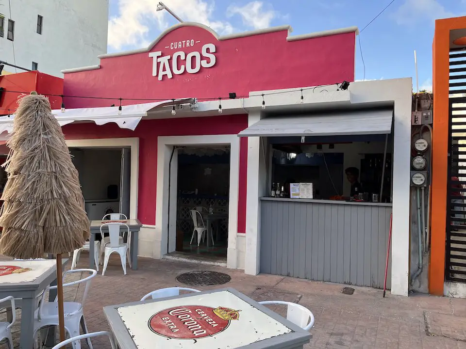 Author's image of Cuatro Tacos in downtown Cozumel. Pink facade with tables on the sidewalk, out front. 