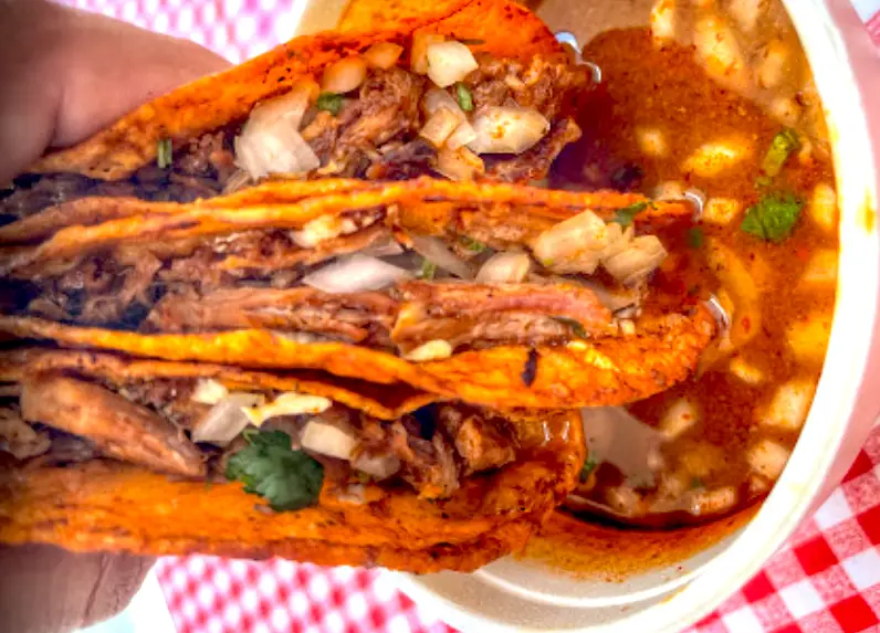 Close up of three quesabirra tacos and a cup of beef broth at Quesabirra el Caribe in Cozumel. 